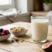 Bicchiere di kefir naturale su superficie in legno con frutti di bosco e cereali integrali, in una cucina luminosa