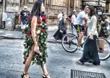 Misteriosa donna vestita di sole rose per le strade di Palermo