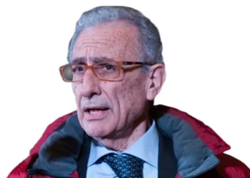 Ritratto di Angelo Attaguile in primo piano, con giacca rossa e camicia azzurra, isolato su sfondo trasparente.