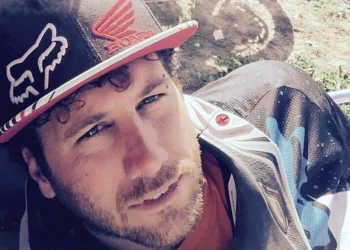 Lorenzo Belfiore in abbigliamento da motocross accanto alla sua moto Honda numero 21.