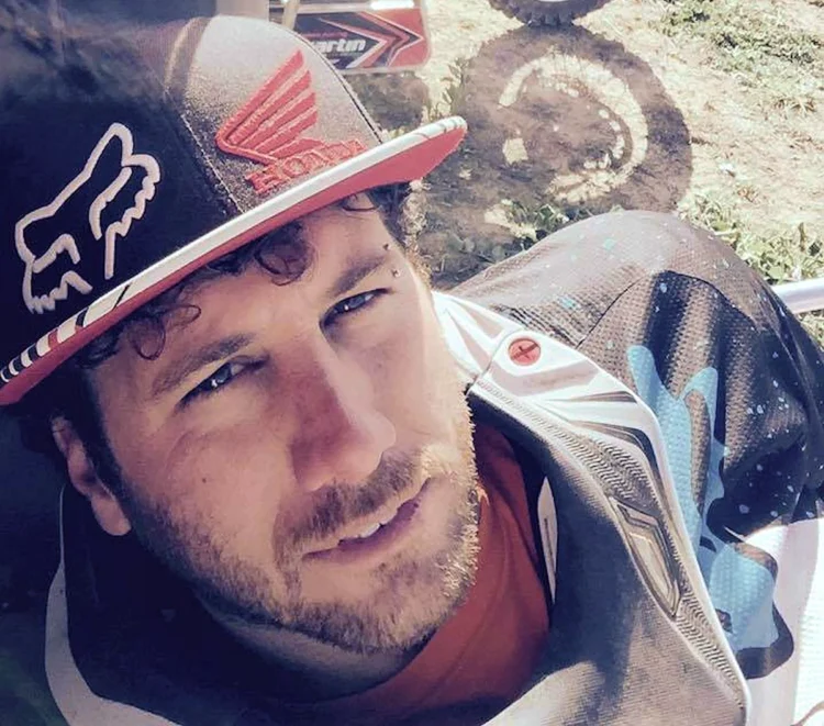 Lorenzo Belfiore in abbigliamento da motocross accanto alla sua moto Honda numero 21.