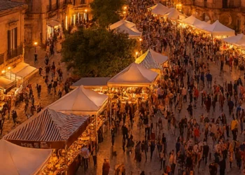 Panoramica del centro storico barocco di Modica al tramonto durante ChocoModica, con stand del cioccolato, luci calde e atmosfera festiva.