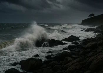 Costa siciliana durante una forte mareggiata con cielo scuro.