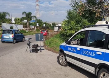 Postazione autovelox mobile della Polizia Locale con apparecchiatura su treppiede e pattuglia ferma a bordo strada