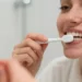 persona adulta che si lava i denti davanti allo specchio, con luce naturale e focus su spazzolino e gengive sane.