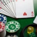 Una vista ravvicinata di un ventaglio di carte da gioco, chip da poker impilate con denominazioni (5, 10, 20), e dadi colorati (rosso, giallo, verde) su un tavolo da gioco in feltro verde.