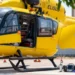 Fotografia ravvicinata dell'elicottero giallo del 118 "ELISUD" con il portellone aperto, attrezzature mediche (monitor, zaino, ossigeno) a terra sulla piazzola dell'Ospedale Maggiore di Modica.