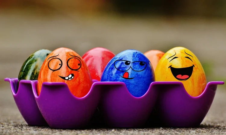 Biglietto d'auguri con la scritta Buona Pasqua 2026 circondato da uova colorate e fiori primaverili.