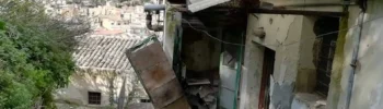 Scorcio di un vicolo storico di Modica con case in pietra antica da ristrutturare