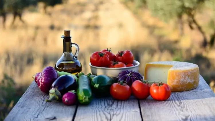 Vista aerea di una tavola mediterranea rustica in campagna siciliana con olio extravergine d’oliva, pomodori di Pachino, formaggio Ragusano e verdure di stagione