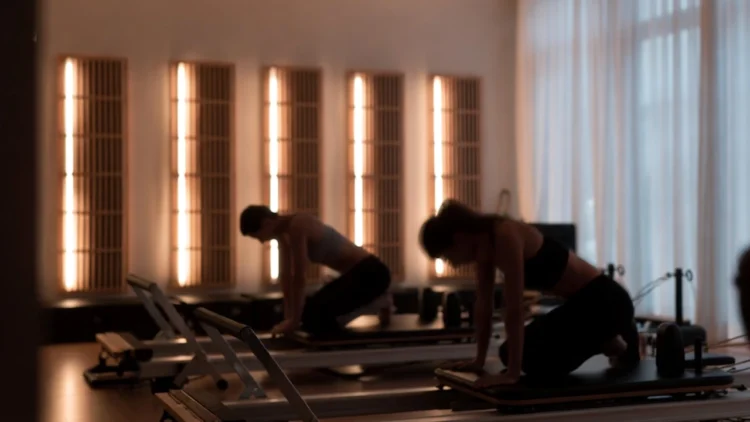 Lezione di infrared pilates in una sala moderna con pannelli infrarossi alle pareti, dei centri benessere italiani.