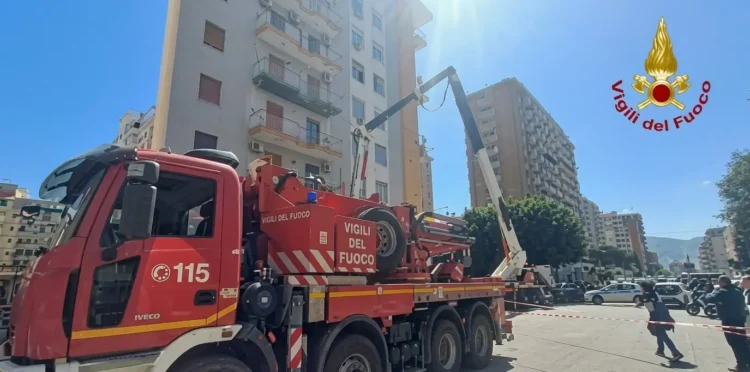 Un camion dei Vigili del Fuoco parcheggiato in via Ruggero Marturano a Palermo, con il braccio meccanico sollevato verso un edificio civile dopo l'incidente mortale sul lavoro.