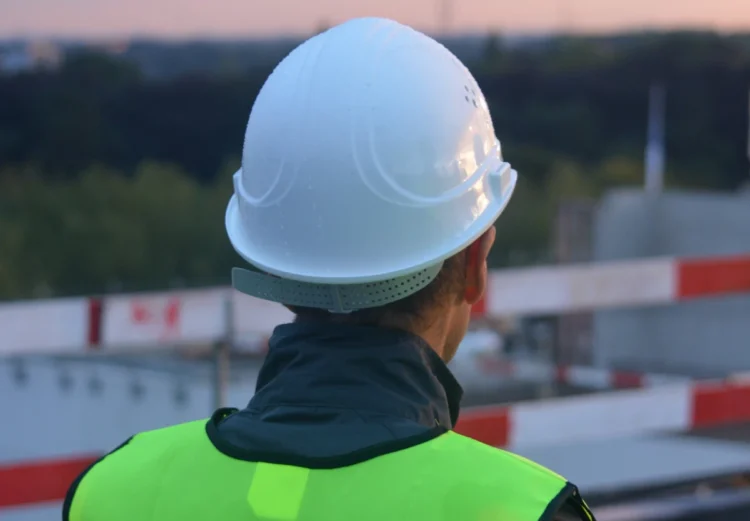 Operai in un cantiere con caschi e dispositivi di protezione mentre seguono le linee guida sulla sicurezza sul lavoro.