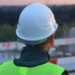 Operai in un cantiere con caschi e dispositivi di protezione mentre seguono le linee guida sulla sicurezza sul lavoro.