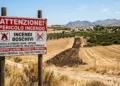 Cartello di prevenzione incendi e fascia parafuoco in un terreno agricolo