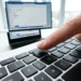 Tastiera di laptop con dito vicino al tasto Stamp per fare uno screenshot su PC Windows da inviare via email