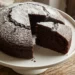 Torta alla Nutella appena sfornata con venature di crema al cioccolato, spolverata di zucchero a velo, su alzata bianca