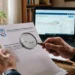 Un pensionato consulta documenti previdenziali e tablet per verificare l'importo dell'assegno INPS.