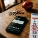 Smartphone con app INPS aperta e monete su un tavolo, riferimento al pagamento Assegno Unico maggio 2026