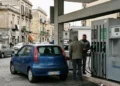 lavoratore che fa rifornimento carburante con auto in stazione di servizio