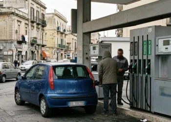 lavoratore che fa rifornimento carburante con auto in stazione di servizio
