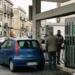 lavoratore che fa rifornimento carburante con auto in stazione di servizio