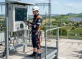 Tecnico Enel al lavoro su una rete elettrica per la transizione energetica, borsa attrezzi e casco di sicurezza