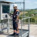 Tecnico Enel al lavoro su una rete elettrica per la transizione energetica, borsa attrezzi e casco di sicurezza