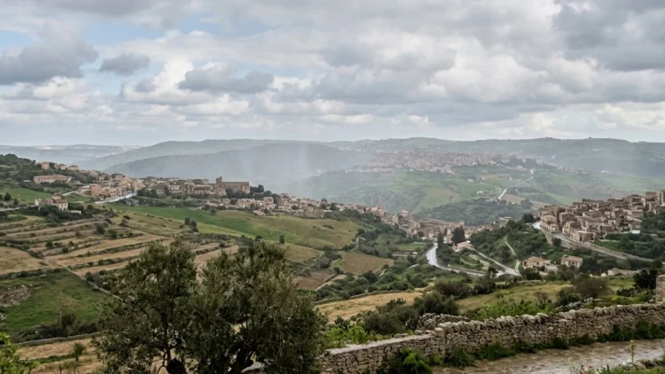Nuvole scure e pioggia su paesaggio siciliano con instabilità meteo