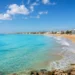 Panoramica della costa ragusana con mare turchese, spiaggia sabbiosa e cielo sereno durante il weekend di fine maggio 2026.