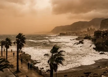 Cielo velato e giallastro sopra la costa siciliana con mare agitato per il vento.
