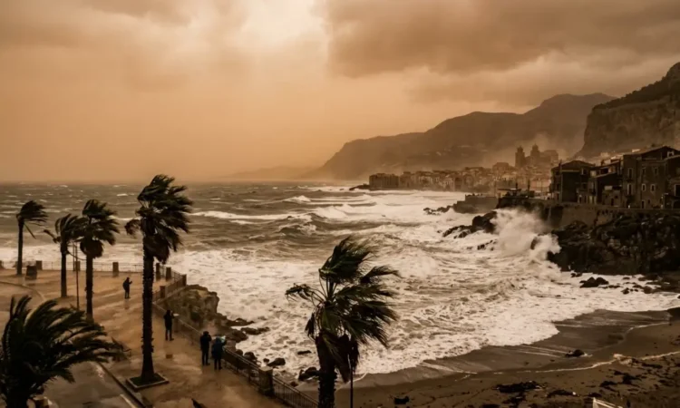 Cielo velato e giallastro sopra la costa siciliana con mare agitato per il vento.