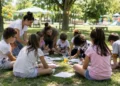 Bambini partecipano ad attività creative all'aperto insieme agli educatori durante un centro estivo in un parco.