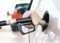 Distributore di carburante con automobilisti in attesa e prezzi alla pompa
