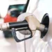 Distributore di carburante con automobilisti in attesa e prezzi alla pompa