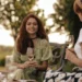 Due donne con abiti estivi sorseggiano un aperitivo all'aperto durante una serata estiva, con look leggeri e informali