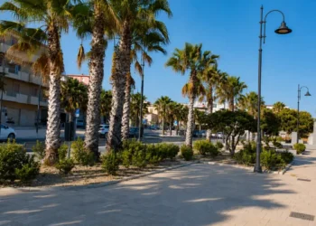 Veduta del centro di Pozzallo con attività commerciali e spazi pubblici in un contesto urbano destinato al turismo.