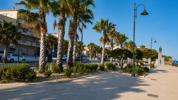 Veduta del centro di Pozzallo con attività commerciali e spazi pubblici in un contesto urbano destinato al turismo.