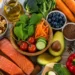 Ciotola con verdure fresche, salmone, frutta, semi e frutta secca, alimenti associati al benessere della pelle in estate