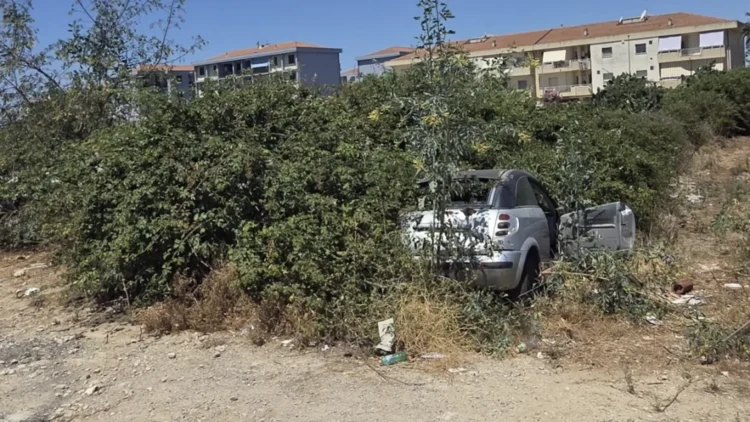 Auto abbandonata tra sterpaglie e vegetazione incolta in un’area degradata di Vittoria.
