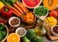 Selezione di frutta, verdura, frutta secca e olio extravergine d'oliva ricchi di nutrienti utili al benessere della pelle durante l'estate