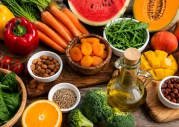 Selezione di frutta, verdura, frutta secca e olio extravergine d'oliva ricchi di nutrienti utili al benessere della pelle durante l'estate