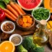 Selezione di frutta, verdura, frutta secca e olio extravergine d'oliva ricchi di nutrienti utili al benessere della pelle durante l'estate