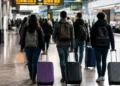 Giovani con valigie e zaini in una stazione ferroviaria, simbolo della mobilità dei laureati dal Sud verso altre regioni