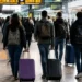 Giovani con valigie e zaini in una stazione ferroviaria, simbolo della mobilità dei laureati dal Sud verso altre regioni