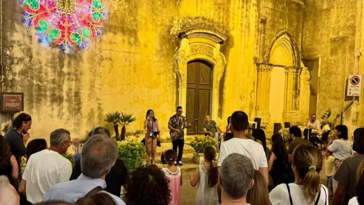 Pubblico assiste a un'esibizione musicale serale durante Ibla in Festa nel centro storico di Ragusa Ibla