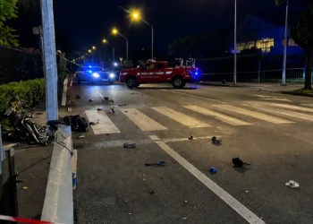 Forze dell'ordine e Vigili del Fuoco bloccano una strada di notte con strisce pedonali e detriti sull'asfalto.