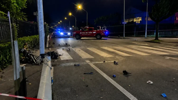 Forze dell'ordine e Vigili del Fuoco bloccano una strada di notte con strisce pedonali e detriti sull'asfalto.