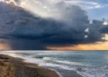 Nuvole temporalesche sul mare della Sicilia con rovesci in lontananza e cielo parzialmente illuminato.