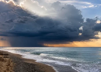 Nuvole temporalesche sul mare della Sicilia con rovesci in lontananza e cielo parzialmente illuminato.